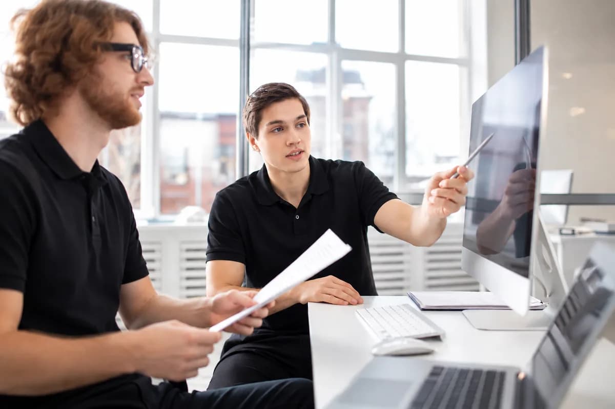 Two engineers reviewing a technical design on a monitor