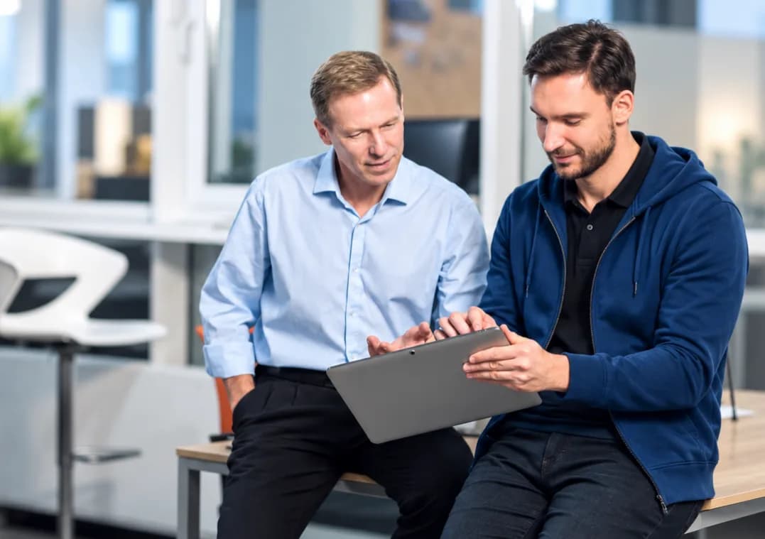 Two colleagues reviewing a tablet together in an office