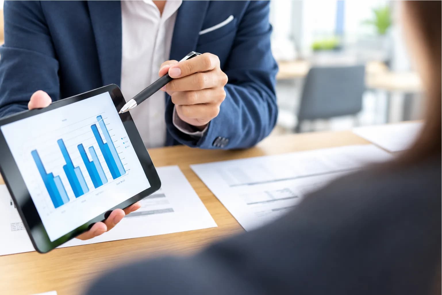 Advisor pointing a pen at a bar chart on a tablet